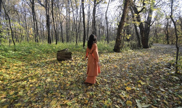 Schöne Frau mit rotem Regenschirm im Herbstwald