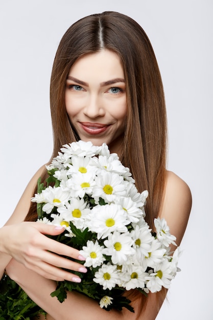 Schöne Frau mit sauberer frischer Haut, die Blumen hält