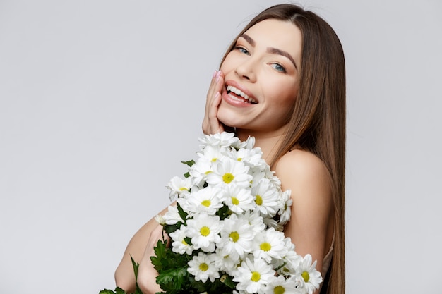 Schöne Frau mit sauberer frischer Haut, die Blumen hält