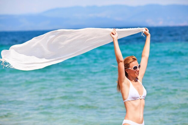 Schöne Frau mit Schal am Strand genießen