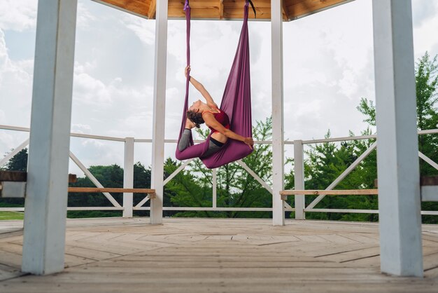 Schöne Frau mit schönem Körper und Bauch, die sich beim Üben von Aerial Yoga ruhig und ausgeruht fühlen