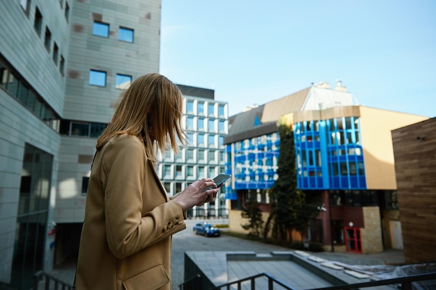 Schöne Frau mit Smartphone auf der Stadtstraße Kaukasisches weibliches Porträt mit Handy