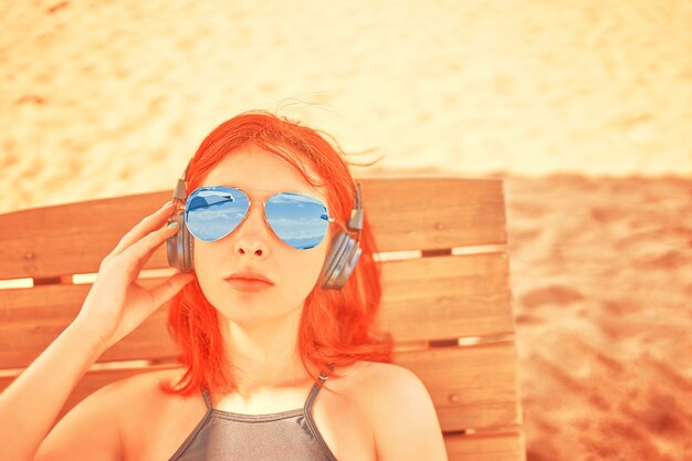 Foto schöne frau mit sonnenbrille musik am strand hören.