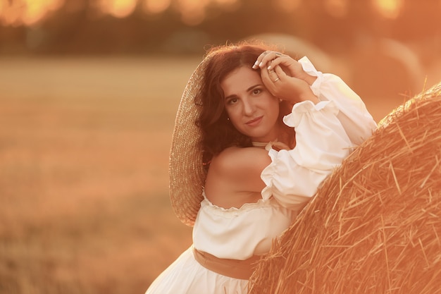 Schöne Frau mit Strohballen im Sommer