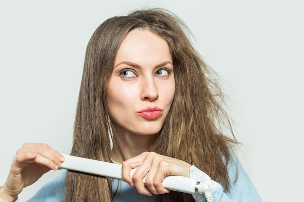 Schöne Frau mit unordentlichem Haar Hairstyling Friseur Haarglätteisen