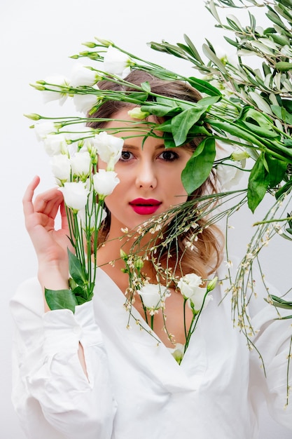 Schöne Frau mit weißen Rosen im Ärmel, Dressing in einem weißen Kleid. Frühlingskonzept oder Valentinstag