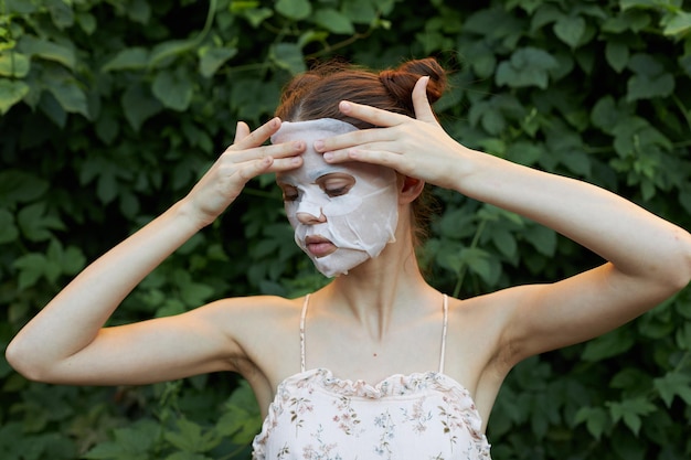 Schöne Frau mit weißer Maske. Berühren Sie das Gesicht mit Ihren Händen und schmieren Sie die Haut