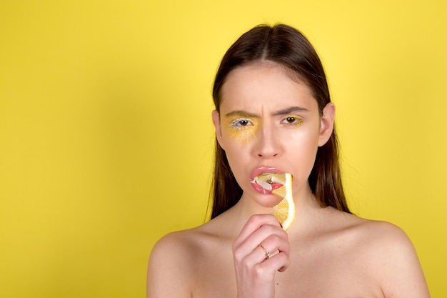 Schöne Frau mit Zitrone und gelbem Make-up