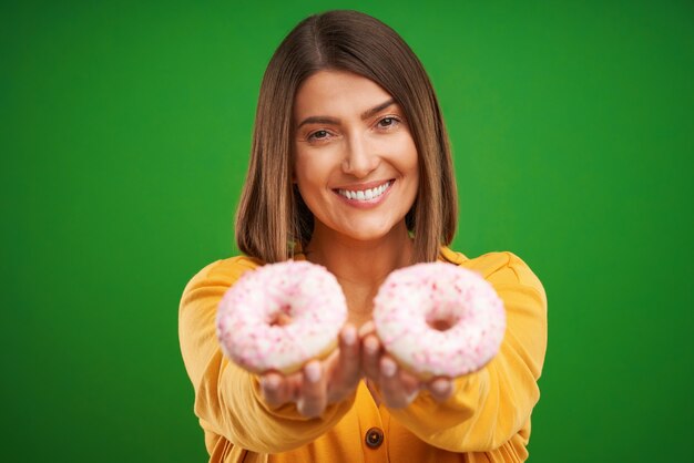 schöne Frau posiert mit Donuts auf grünem Hintergrund