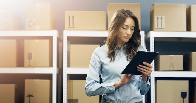 Schöne Frau, Postangestellter mit Tablet-Gerät in Händen, die im Postamt arbeiten.