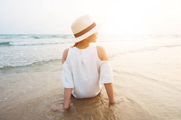 schöne Frau sitzt am Sandstrand.