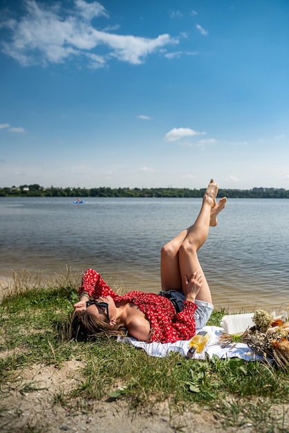 Schöne Frau sitzt, um sich in der Nähe des Teichs im Park zu entspannen und die Natur im Freien zu genießen