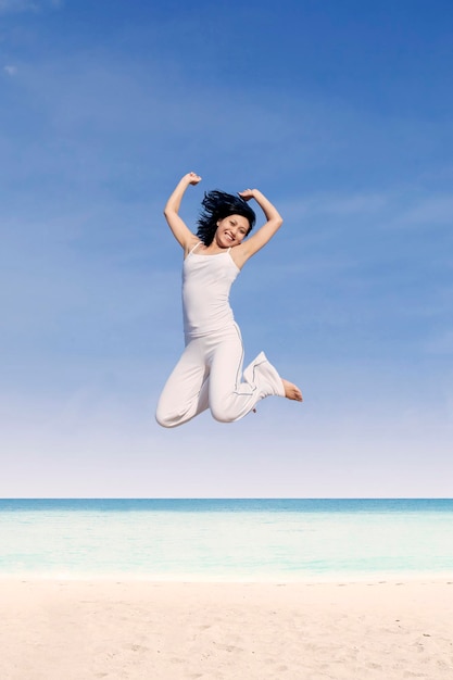 Schöne Frau springt am Strand