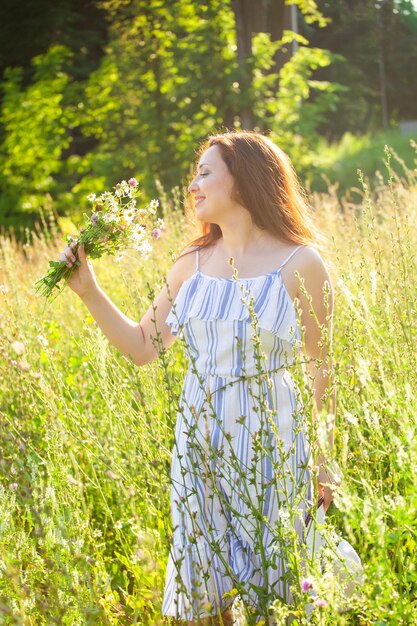 Foto schöne frau steht auf dem feld bei blühenden pflanzen