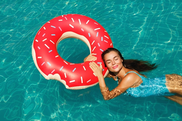 Schöne Frau und aufblasbarer Schwimmring in Form des Donuts