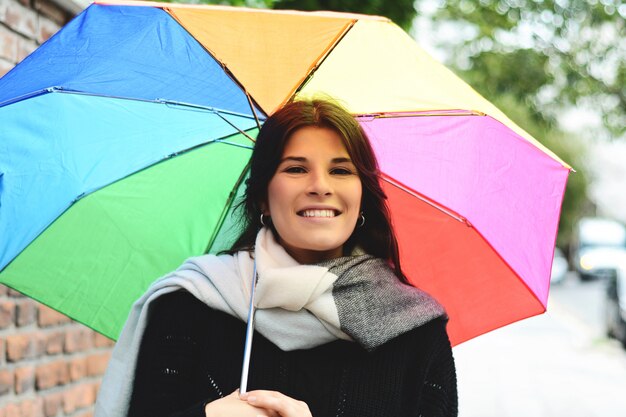 Schöne Frau unter Regenbogenregenschirm