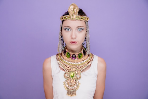 Schöne Frau wie Kleopatra im alten ägyptischen Kostüm, die auf Lila überrascht wird