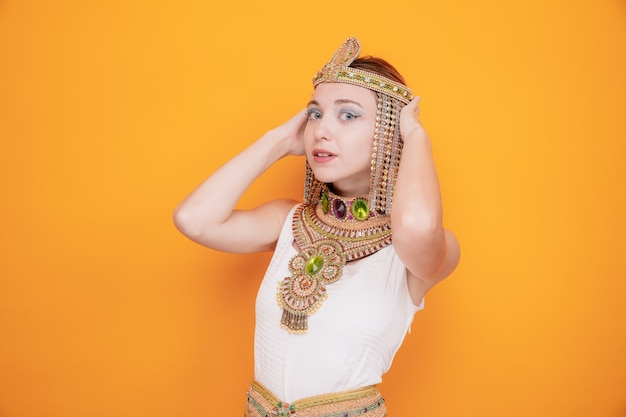 Schöne Frau wie Kleopatra im alten ägyptischen Kostüm glücklich und selbstbewusst lächelnd auf Orange