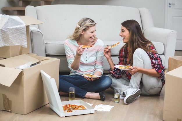 Schöne Frau zwei, die Pizza im neuen Haus isst