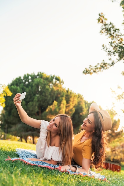 Schöne Frauen, die ein Selfie-Porträt im Park machen. Freunde und Sommerkonzept.