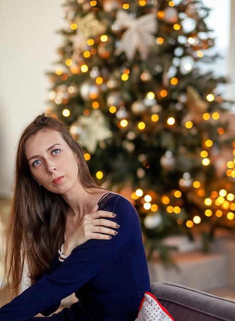 Schöne Frauen schmücken den Weihnachtsbaum beim Weihnachtsfest. Glücklich lächelnde Teenagerinnen feiern Weihnachten im heimischen Wohnzimmer