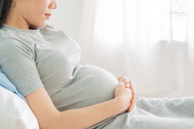 Schöne Frauen schwanger auf dem Bett