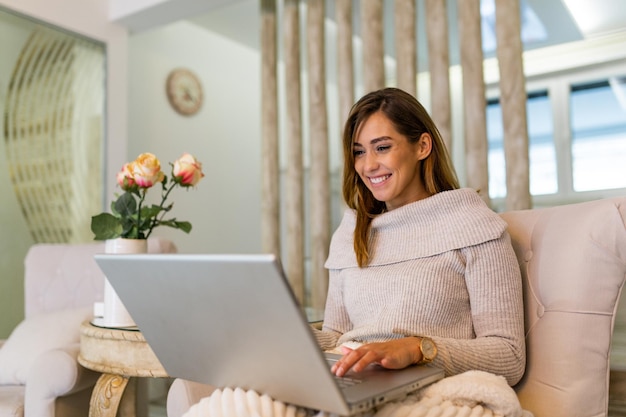 Schöne Freiberuflerin, die Informationen für die Planung von Projekten notiert, die Remote-Job über Laptop-Computer ausführen. Mädchen lachen beim Lesen von E-Mails auf einem modernen Laptop.