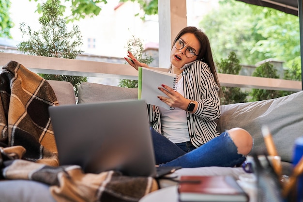 Schöne freiberufliche Frau arbeitet zu Hause und spricht Handy.