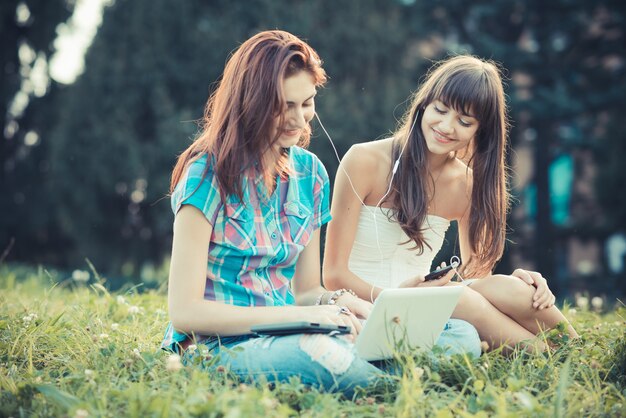 Foto schöne freunde der jungen freunde der hippie-schwestern, die tablette und smartphone verwenden