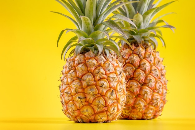 Schöne frische Ananas lokalisiert auf hellem gelbem Hintergrund, sommerliches saisonales Fruchtdesignideenmusterkonzept, Kopienraum, Nahaufnahme