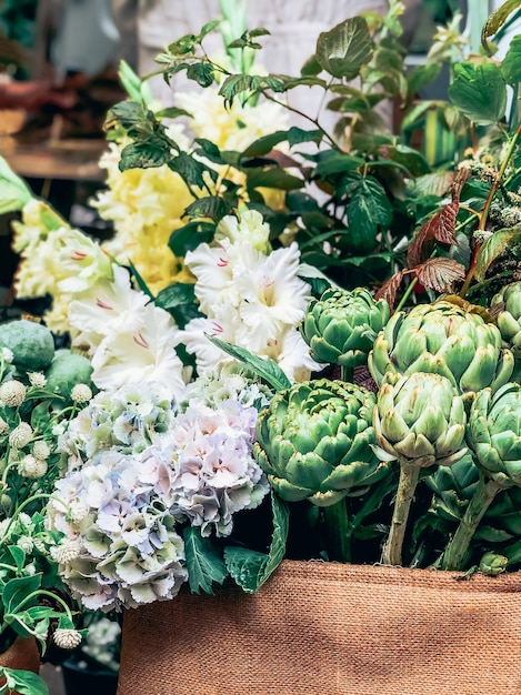 Schöne frische dekorative grüne Artischocken und andere Blumen im kleinen Blumengeschäft