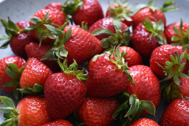 Schöne frische Erdbeeren in einem Teller auf Betongrund.