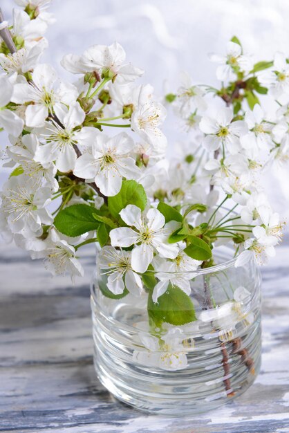 Schöne Fruchtblüte im Glas auf dem Tisch auf grauem Hintergrund