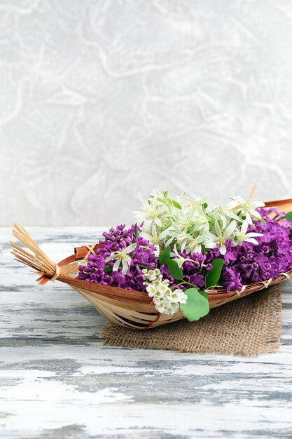 Schöne Frühlingsblumen im Weidenkorb auf Holztisch hautnah