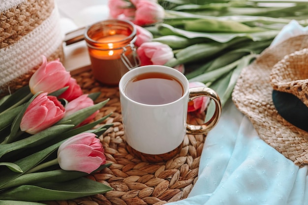 Schöne Frühlingskomposition eine Tasse Tee, Tulpen, eine Kerze und ein Hut