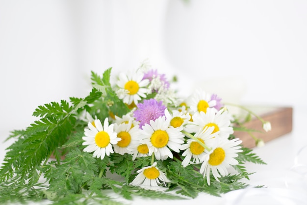 Schöne Gänseblümchen und andere Blumen auf einem weißen Tisch.