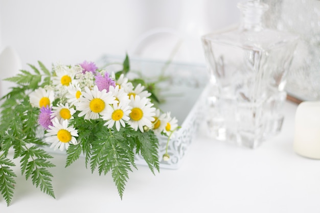 Schöne Gänseblümchen und andere Blumen auf einem weißen Tisch.