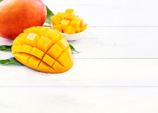 Schöne gehackte Mango mit grünen Blättern auf hellweißem Holzhintergrund Oben Ansicht von oben flach liegender Kopierbereich Nahaufnahme Tropisches Fruchtkonzept