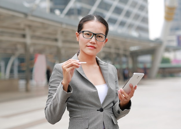 Schöne Geschäftsfrau, die draußen an einem Smartphone in ihren Händen arbeitet.