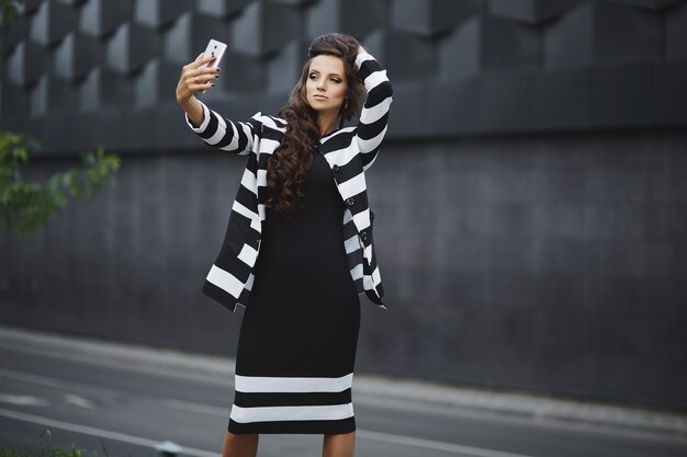 Schöne Geschäftsfrau, die glamourösen und verführerischen Ausdruck macht und Selfie auf einem Smartphone nimmt