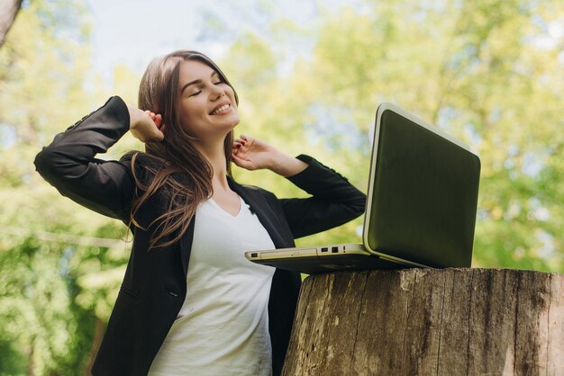 Schöne Geschäftsfrau im Anzug mit Laptop-Computer im Park