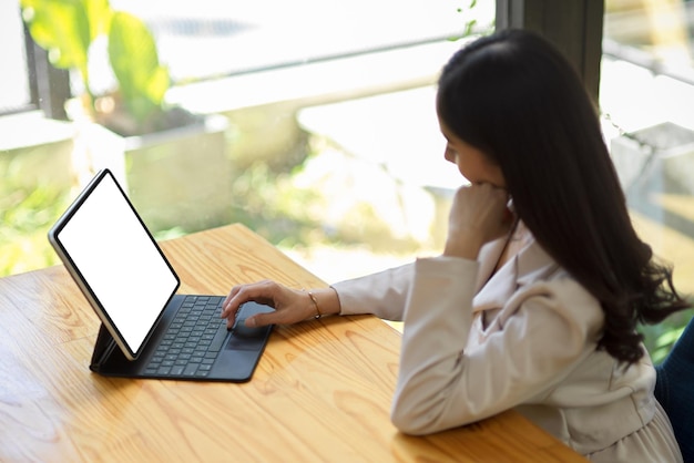 Schöne Geschäftsfrau im weißen Anzug, die am Tablet-Computer arbeitet und auf der Tablet-Tastatur tippt