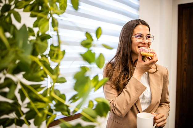 Schöne Geschäftsfrau isst gerne Donuts bei der Arbeit