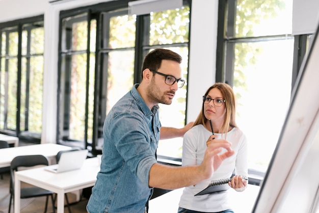 Schöne Geschäftsfrau und Mann, die mit Flipchart arbeitet.