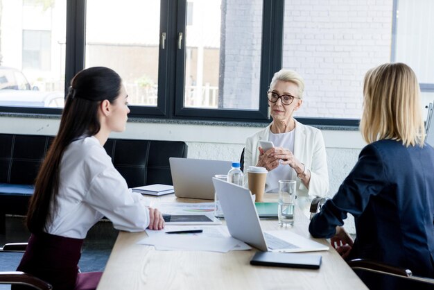 schöne Geschäftsfrauen mit Laptops und Smartphones bei einem Treffen im Büro