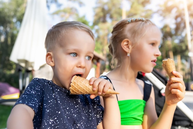 Schöne Geschwister essen Eis, während sie draußen sitzen