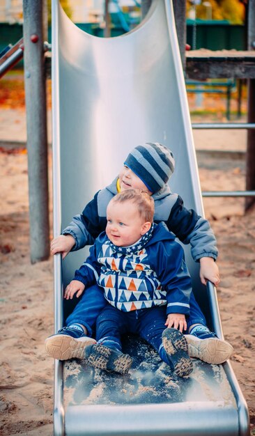 Foto schöne geschwister sitzen auf der rutsche auf dem spielplatz