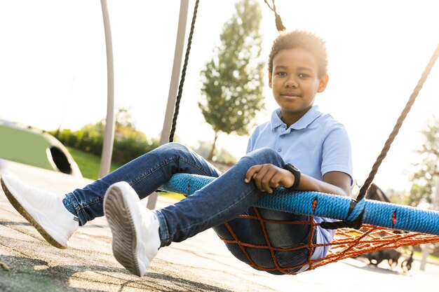 Schöne glückliche afroamerikanische Familie im Park - Schwarze Familie, die Spaß im Freien hat, süßer Junge, der auf der Schaukel spielt