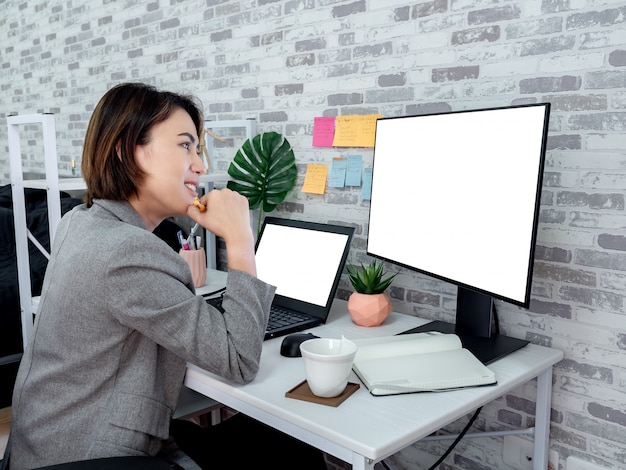 Schöne glückliche asiatische Frau, die mit Laptop-Computer in ihrem Zimmer, Eigentumswohnung arbeitet.