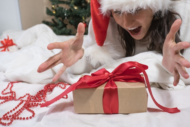 Schöne glückliche brünette Frau macht ein Selfie per Telefon in einem weißen Pullover und einer Weihnachtsmütze und